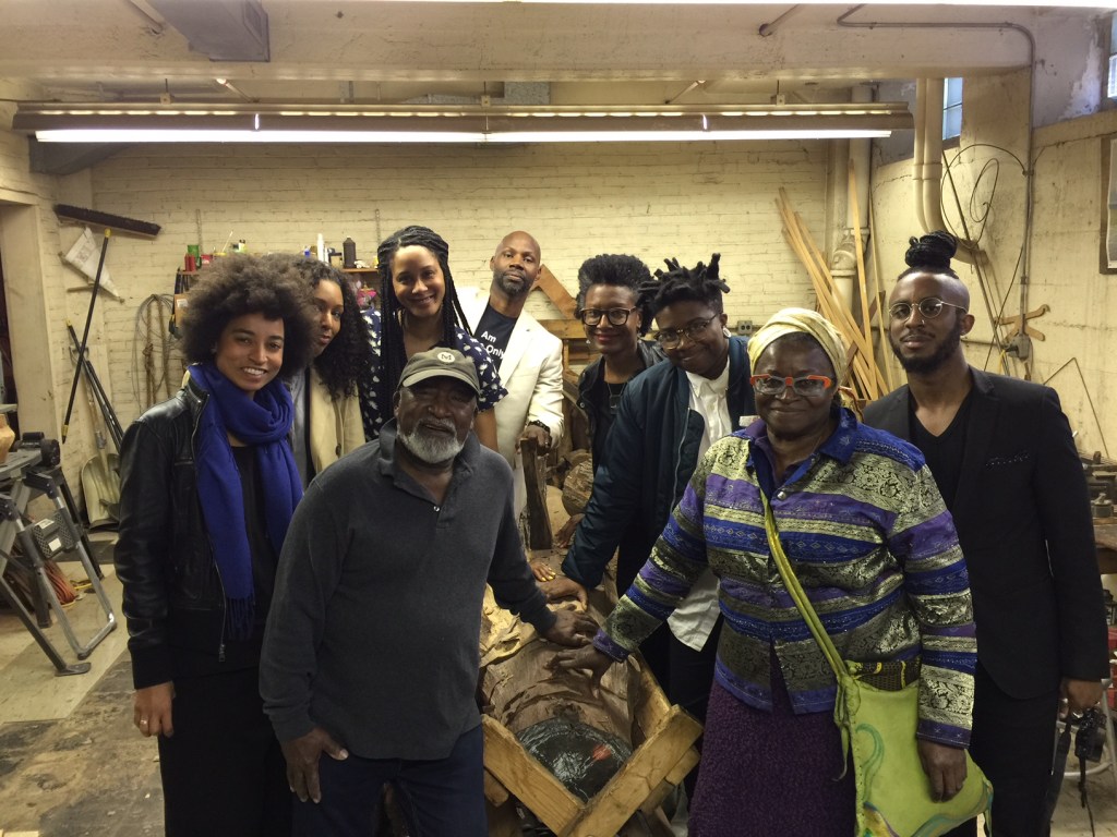 a group of black artists standing in an art studio with Brick walls - everyone is smiling 