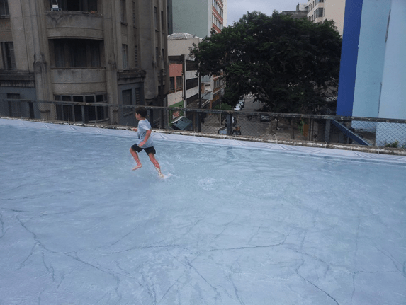 a child running through a shallow Olympic sized pool on a highway in São Paulo