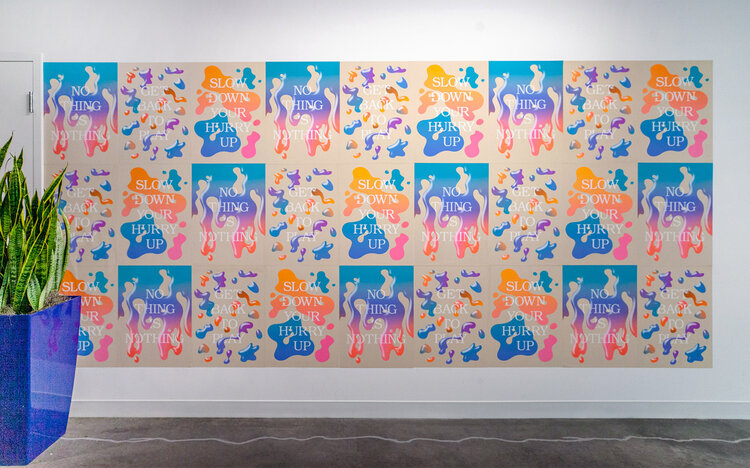 covering an entire wall, this piece is made up of 3 smaller pieces that are repeated and arranged to be one canvas. the piece uses blob shapes, bright colors: orange, blue pink, and purple , and the text in white reads: "No Thing Is Nothing", "Get Back to Play", and "Slow Down your Hurry Up"
